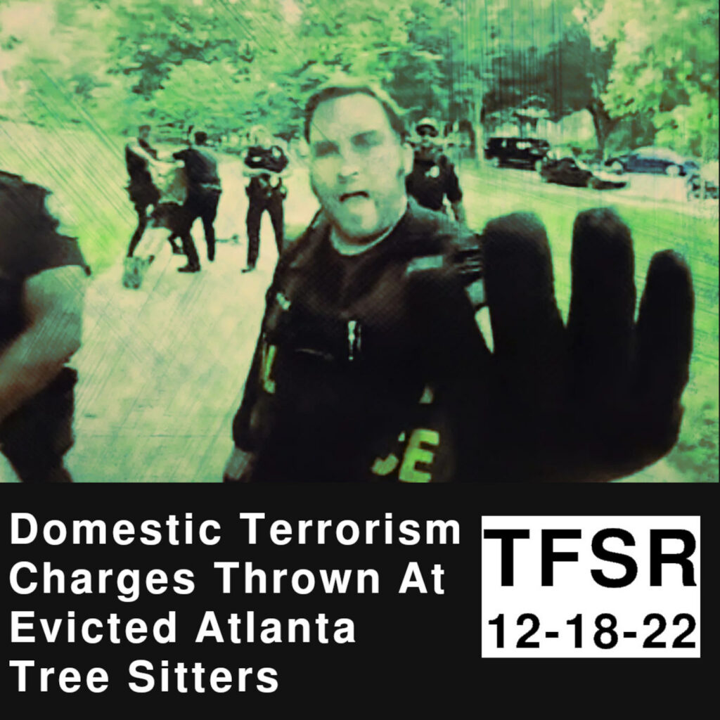 Green-tinged image of cops trying to stop photo while arrests happen in background at Atlanta Forest protest